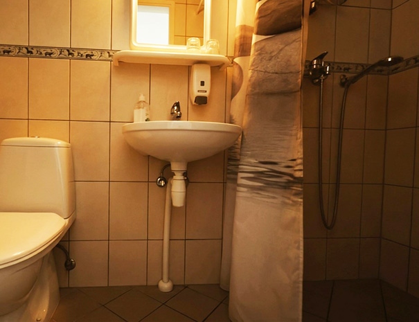 Interior of the private bathroom in the single room at Hostel Lõuna, showing the shower, sink, mirror, and toilet.