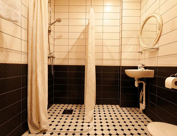 The spacious, bright, and stylishly furnished private bathroom of the Suite at Hostel Lõuna, featuring a modern shower and cute mirror.