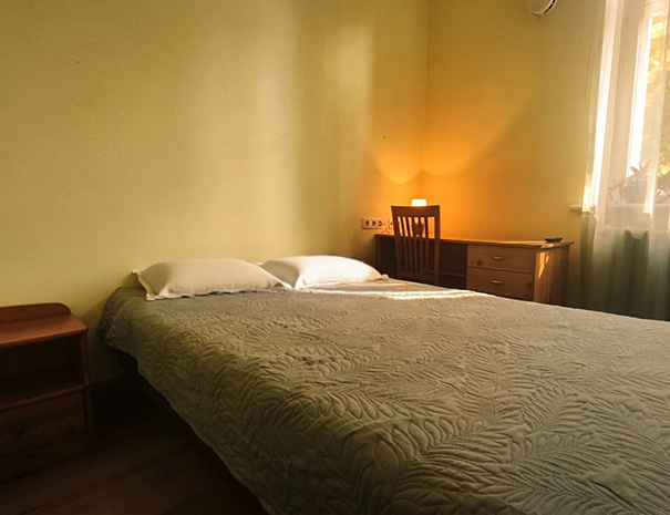 Hostel Lõuna ühekohaline tuba mugava voodi, kirjutuslaua ja suure aknaga, millest avaneb vaade rohetavale pargile.