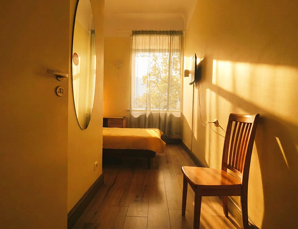 Vaade Hostel Lõuna ühekohalise toa ukselävelt, kus on näha voodi, teler, pargivaatega aken ja uks privaatsesse vannituppa.