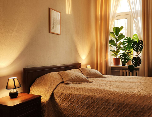 Hostel Lõuna ruumika sviidi magamistuba suure laia voodi, hubase valgustuse ja roheliste toataimedega aknal.