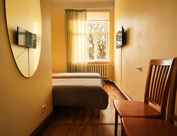 Vaade Hostel Lõuna twin toa lävelt, kus on näha kaks voodit, teler, pargivaatega aken ja uks privaatsesse vannituppa.